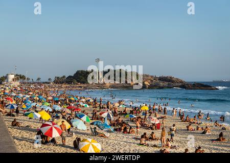 Stark überfüllte Küste von Arpoador mit Halbinsel Arpoador Rock (Pedra do Arpoador) im hinteren Teil des Sommers, am späten Nachmittag, klarem blauem Himmel. Stockfoto