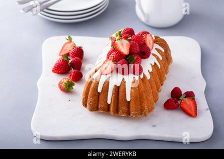 Den Kuchen mit Zuckerglasur und roten Beeren draufschlagen Stockfoto