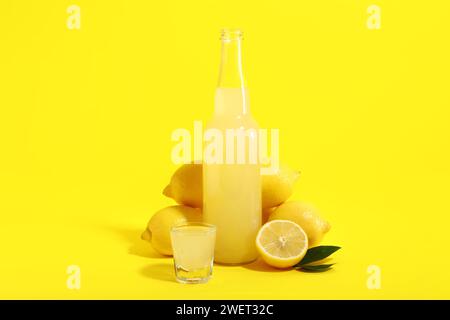 Schuss und Flasche leckeres Limoncello auf gelbem Hintergrund Stockfoto