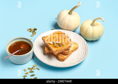 Teller mit süßer Kürbismarmelade und Samen auf blauem Hintergrund Stockfoto