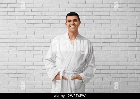 Porträt eines hübschen jungen Mannes im Bademantel auf weißem Backsteinhintergrund Stockfoto
