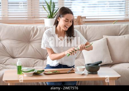 Schöne junge Frau, die Aloe Vera Gel im Wohnzimmer herstellt Stockfoto