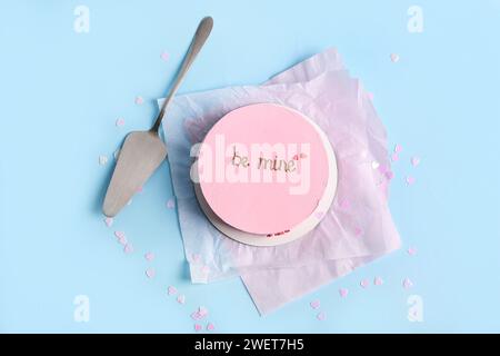 Pinke bento-Torte mit Spachtel und Konfetti auf blauem Hintergrund. Valentinstag-Feier Stockfoto