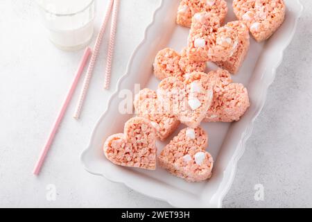 Rosafarbene herzförmige Reis-Krispie-Leckereien mit Milch, hausgemachte süße Leckereien zum Valentinstag Stockfoto