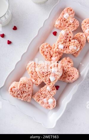 Rosafarbene herzförmige Reis-Krispie-Leckereien mit Milch, hausgemachte süße Leckereien zum Valentinstag Stockfoto
