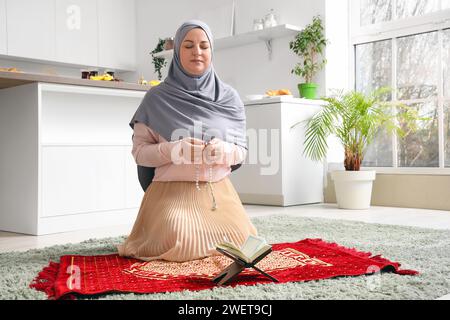 Reife muslimische Frau betet mit Perlen in der Küche. Ramadan-Feier Stockfoto