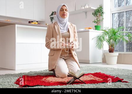 Junge muslimische Frau betet mit Perlen in der Küche. Ramadan-Feier Stockfoto