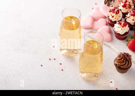 Champagner zum Valentinstag mit Dessert-Wurstplatte mit Cupcakes, Keksen, frischen Beeren und Schokolade Stockfoto