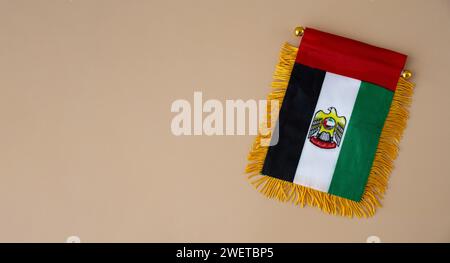 Nationales Symbol der VAE. Kleine Flagge der Vereinigten Arabischen Emirate mit Wanderfalke auf neutralem beigem Hintergrund. Kopieren Sie den Platz für Ihren Text. Das Konzept der Unabhängigkeit des Nationaltages Stockfoto