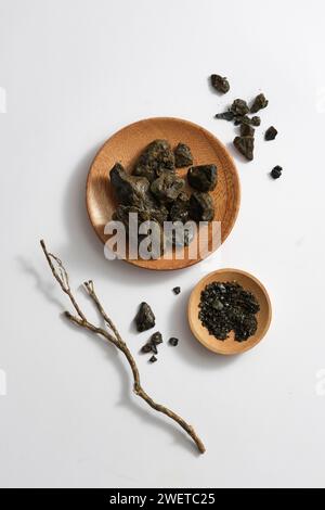 Aloe-Harz bildet, wenn es konzentriert wird, harte schwarze Klumpen, die auf Holzplatten auf hellem Hintergrund platziert werden. Werbeszenen für traditionelles C Stockfoto