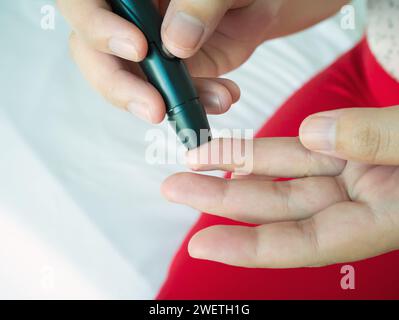 Frau mit lanzettfischchens am Finger, Diabetes Test überprüfung der Blutzuckerspiegel Stockfoto