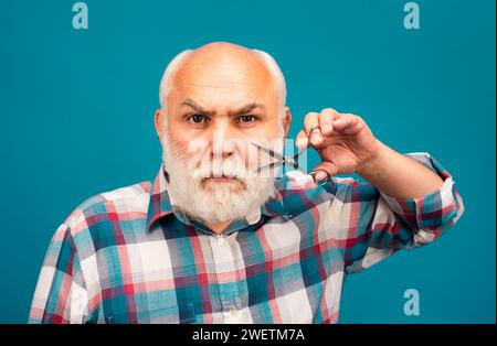 Friseurschere. Mann mittleren Alters. Porträt eines alten kahlen Mannes bärtiger Mann mit grauem Schnurrbart. Stockfoto