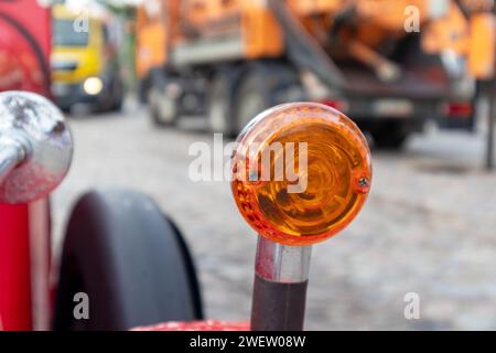 Eine orange Autolampe auf einem roten Fahrzeugflügel auf dem Hintergrund einer schweren Maschine Stockfoto