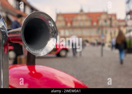 Metallhorn auf rotem Auto-Kotflügel auf dem Hintergrund der Straßen der Stadt Stockfoto