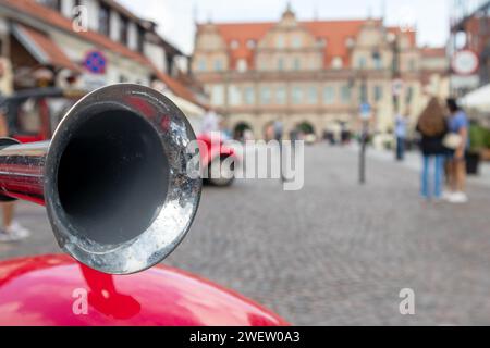 Metallhorn auf rotem Auto-Kotflügel auf dem Hintergrund der Straßen der Stadt Stockfoto