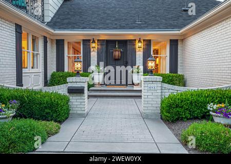 Weißes Backsteinhaus mit schwarzer Tür und grauen Fensterläden Stockfoto
