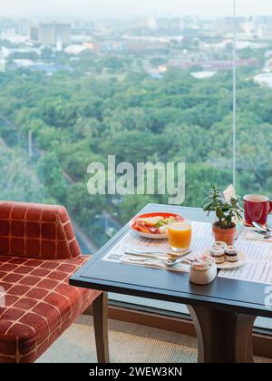 Frühstück in einem Hochhaus-Hotel in Manila, Philippinen, mit verschwommenem Blick auf die Stadt im Hintergrund. Stockfoto