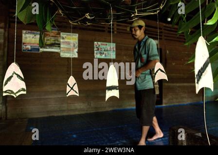 Stücke traditioneller dekorativer Holzschnitzereien hängen unter einem Opferkorb im Langhaus der Gemeinde Dayak Tamambaloh Apalin im Dorf Sungai Uluk Palin (Sungulo Palin), Putusibau Utara, Kapuas Hulu, West Kalimantan, Indonesien. Kultur ist ein unverzichtbarer Bestandteil jeder Entwicklung, wenn sie nachhaltig sein soll, und es ist von entscheidender Bedeutung, dass jeder Mensch und jede Gemeinschaft ihre kulturellen Rechte frei ausüben kann, so eine Pressemitteilung der Vereinten Nationen vom Oktober 2022. „Kultur ist eine Möglichkeit und ein Motor für nachhaltige Entwicklung“, so Alexandra Xanthaki, Expertin für kulturelle Rechte. Stockfoto