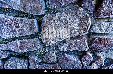 Die Textur großer Steine an der mit Raureif bedeckten Wand. Stockfoto