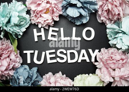 Hallo Dienstag Buchstabe mit Blumendekoration auf schwarzem Hintergrund Stockfoto