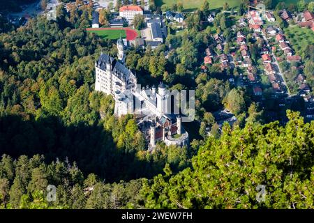 Aus der Vogelperspektive auf das Schloss Neuschwanstein und die umliegenden Häuser des Dorfes Hohenschwangau im Herbst. Stockfoto