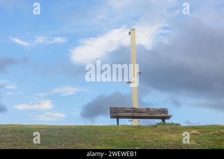 Bank auf dem Gras vor blauem Himmel mit Wolken Stockfoto