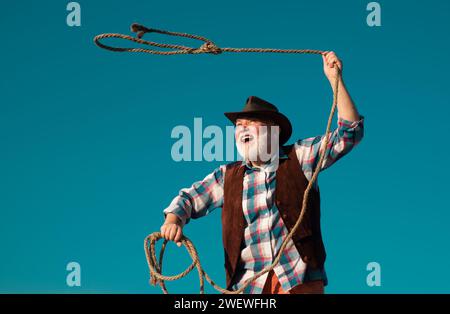 Alter Wilder Westen Cowboy mit Seil. Bärtiger westlicher Mann wirft Lasso mit brauner Jacke und Hut fangen Pferd oder Kuh. Stockfoto