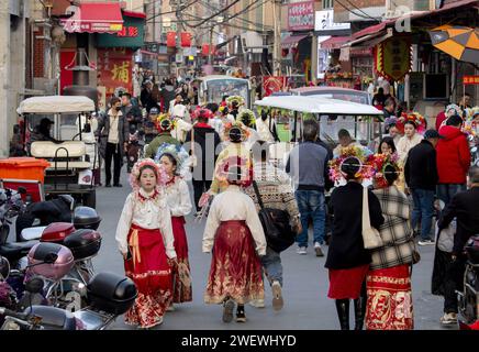 (240127) -- QUANZHOU, 27. Januar 2024 (Xinhua) -- Touristen mit blumigen Kopfbedeckungen werden im Dorf Xunpu der Stadt Quanzhou, südöstlicher chinesischer Provinz Fujian, 26. Januar 2024 gesehen. Die blumigen Kopfbedeckungen von Xunpu, auch „Overhead Gardens“ genannt, sind eine Signatur der „Xunpu Women Customs“, die 2008 als nationales immaterielles Erbe gelistet wurde. Anfang 2023 zogen sie Millionen von Augen in der Cyber-Welt an, gefolgt von einem nachhaltigen Touristenboom im Dorf, wo Besucher buchstäblich ihre Köpfe in sie stecken können. Fotoshooting, Gastronomie und andere Dienstleistungen im Gastgewerbe haben die Einkommensquelle diversifiziert f Stockfoto