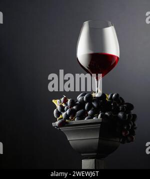 Blaue Trauben und ein Glas Rotwein auf schwarzem Hintergrund. Seiten- und Unteransicht. Selektiver Fokus. Stockfoto