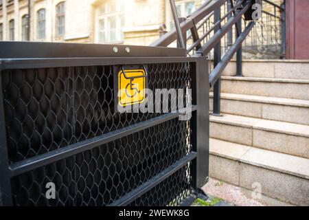 Elektrischer Plattformlift an der Gebäudetreppe für behinderte Menschen mit Rollstuhlschild an der alten Stadtstraße. Aufzug Treppenlift Rampe Mechanismus für Stockfoto