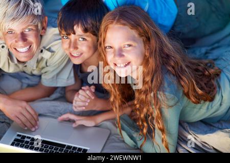 Kinder, Portrait und entspannen Sie mit Laptop auf dem Boden zusammen mit Glück und Online-Spielen für Urlaub oder Urlaub. Kinder, lächeln und spielen mit Stockfoto