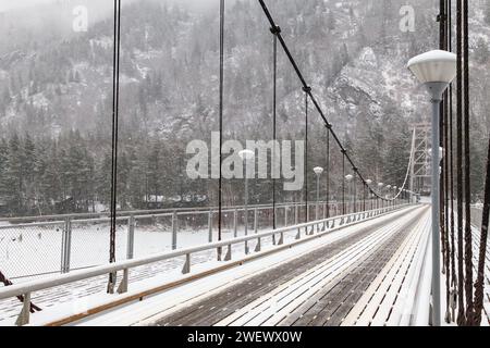 Metall-Hängebrücke für Autos und Fußgänger im Altai-Gebirge im Winter mit Schnee und Nebel auf den Bäumen ohne Menschen. Malerischer Platzgewinn Stockfoto