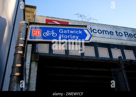 Die Eisenbahnbrücke neben dem Bahnhof in Redhill Surrey mit Welcome to Redhill Schild und britischem Eisenbahnlogo mit Straßen- und Radrouten der A25. Stockfoto