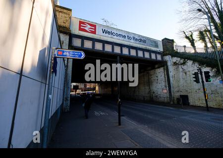 Die Eisenbahnbrücke neben dem Bahnhof in Redhill Surrey mit Welcome to Redhill Schild und britischem Eisenbahnlogo mit Straßen- und Radrouten der A25. Stockfoto