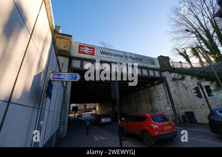 Die Eisenbahnbrücke neben dem Bahnhof in Redhill Surrey mit Welcome to Redhill Schild und britischem Eisenbahnlogo mit Straßen- und Radrouten der A25. Stockfoto