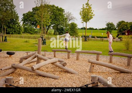 Die beiden Mädchen laufen auf Holzstämmen auf einem Spielplatz Stockfoto