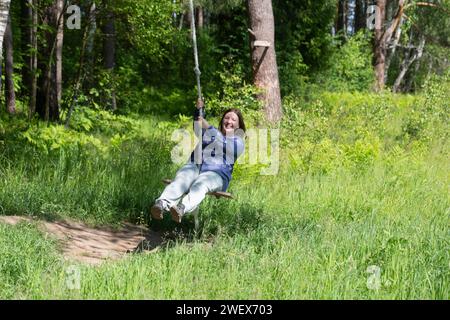 Frau auf einer Seilschaukel im Wald Russland Jaroslawl 1. August 2023 Stockfoto