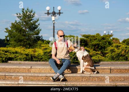 Ein kahler Mann in den dreißiger Jahren, der eine Sonnenbrille mit einem großen Hund trug, im Sommer draußen Russland, Jaroslawl, 10. August 2023 Stockfoto