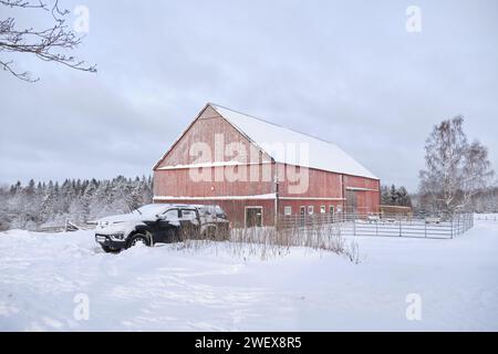 Typisch schwedisches rot lackiertes Landwirtschaftsgebäude in Bredebolet in Skaraborg im Vaestra Goetaland in Schweden im Winter Stockfoto