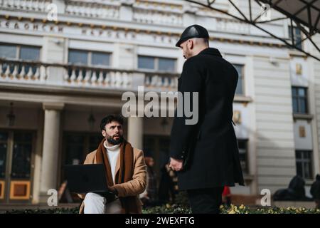 Zwei Geschäftsleute treffen sich vor dem historischen Gebäude mit einem Laptop Stockfoto