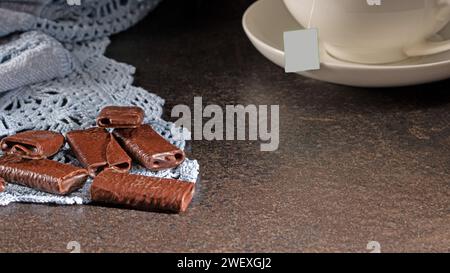 Eine einladende Teeumgebung am Abend mit köstlichen Schokoladengerichten und einer dampfenden heißen Tasse Tee schaffen das perfekte Ambiente für eine gemütliche und entspannende Atmosphäre Stockfoto