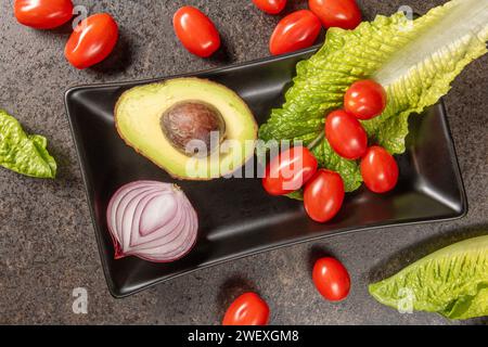 Eine Auswahl an frischem und farbenfrohem Gemüse, einschließlich Tomaten, Paprika, Karotten und Brokkoli, kunstvoll auf dunklem Hintergrund für A s angeordnet Stockfoto