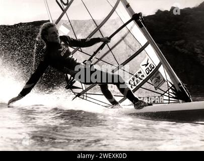 Beim Windsurfen im Mumbles Yachtclub folgt der Matrose Julian Anderson seiner Hand im Gefolge von seinem Board, während sie auf eine Schiene steigt. Stockfoto