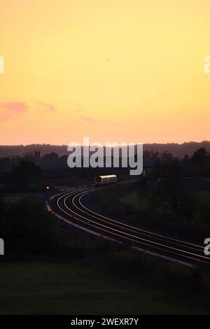 Der Zug der Chiltern Railways Class 168 Clubman fährt über Charlton-on-Otmoor auf der Bicester-Verbindung an einem Teil der Varsity-Eisenbahnstrecke vorbei und fängt den Sonnenuntergang ein Stockfoto