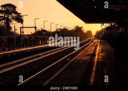 Sonnenaufgang am Bahnhof Bicester North auf der Hauptstrecke von Chiltern mit goldener Sonne, die von der Bahnstrecke mit farbigen Lichtsignalen strahlt. Stockfoto