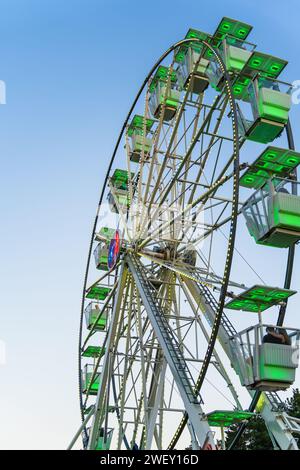 Vergnügungsfahrt gegen blauen Himmel. Nahaufnahme mit einem weißen Riesenrad bei Sonnenuntergang. Stockfoto