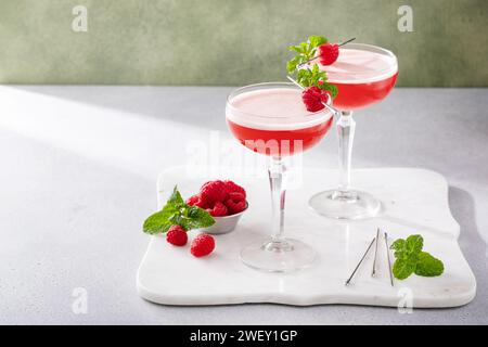 Himbeer-Martini in Coupé-Gläsern garniert mit frischen Himbeeren und Minzblättern Stockfoto