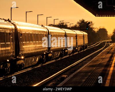 Aufgehende Sonne leuchtet von einem Zug der Chiltern Railways MK3 am Bahnhof Bicester Nord Stockfoto