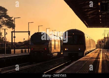 Chiltern Railways der Baureihe 68 Lokomotive 68013 und Baureihe 168 168002 am Bahnhof Bicester North, wo sie die aufgehende Sonne mit einem goldenen Glanz erstrahlen lassen Stockfoto