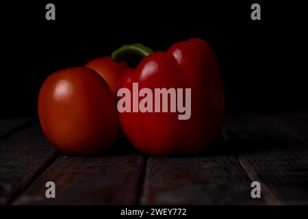 Rote Paprika und Tomaten auf schwarzem Hintergrund Stockfoto